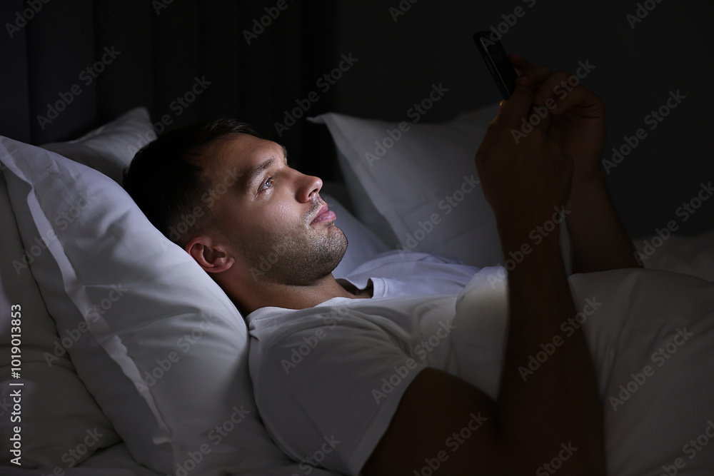Fototapeta premium Bad habit. Man using smartphone in bed at night