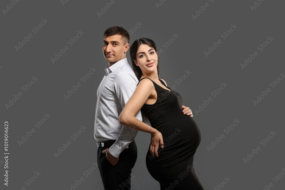 Beautiful pregnant woman with her husband on grey background Beautiful pregnant woman with her husband on grey background
