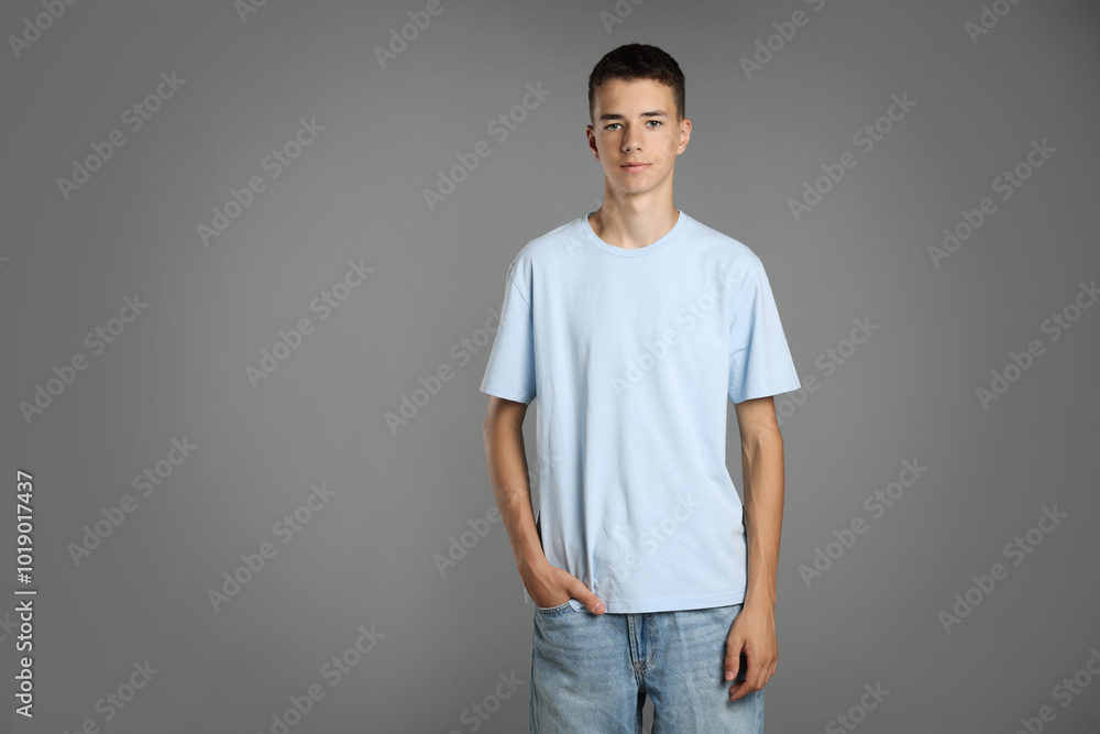 Teenage boy wearing light blue t-shirt on grey background, space for text Teenage boy wearing light blue t-shirt on grey background, space for text