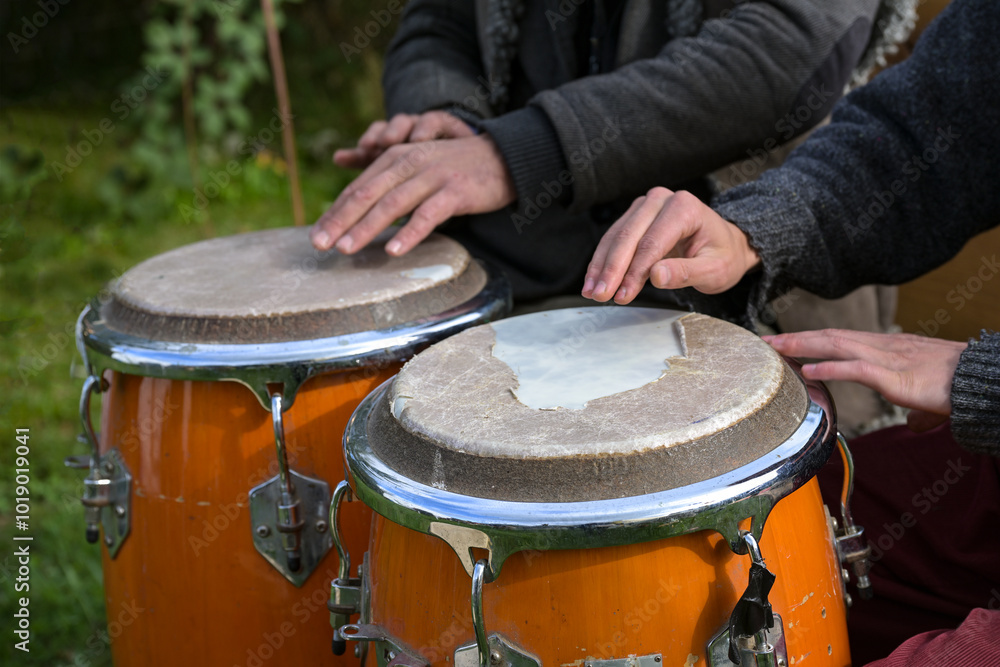 Obraz premium Two musicians playing conga with worn drumskin on an outdoor festival, musical instrument for Latin and Afro-Cuban music, salsa, jazz and more played as hand drums, selected focus
