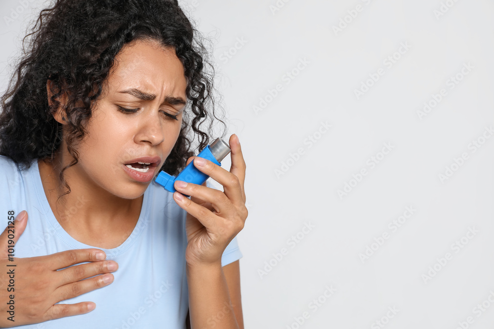 Young woman using asthma inhaler on white background. Space for text Young woman using asthma inhaler on white background. Space for text