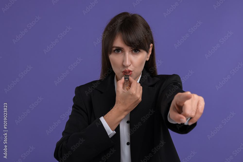 Young woman blowing whistle on purple background Young woman blowing whistle on purple background