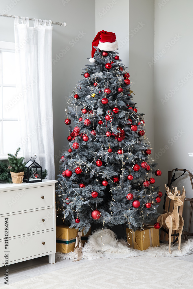 Obraz premium Interior of living room with decorated Christmas tree, chest of drawers, fireplace and gift boxes