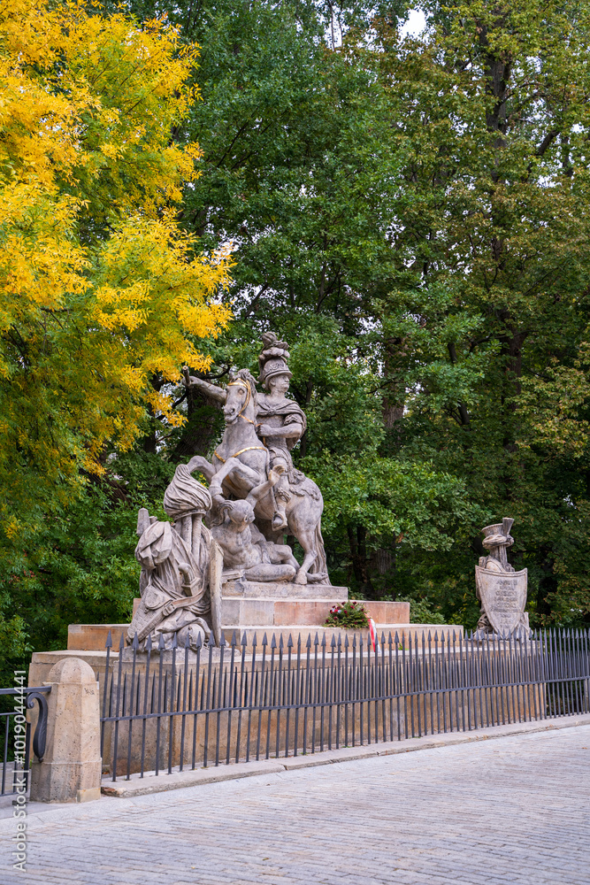 Historic Stone Monument Surrounded by Colorful Autumn Trees, King Jan III Sobieski monument in Warsaw, Poland.