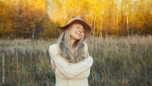 Photography Happy smiling mature woman hugs herself in autumn park enjoying warm weather on