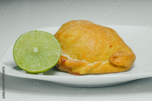 Empanas de harina, en plato blanco, acompañado de medio limón, sobre fondo blanco. photo