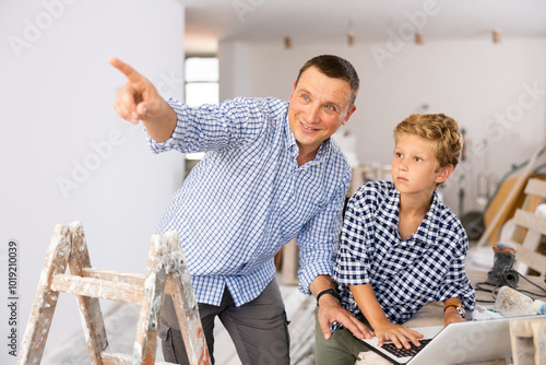 Portrait of man architect and boy using laptop while discussing working process in house being renovated photo