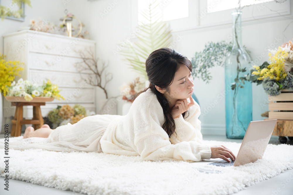 Profile of a young, thinking, distressed, cute, white knit woman in a white knit studying on a computer in a prone position. Profile of a young, thinking, distressed, cute, white knit woman in a white knit studying on a computer in a prone position.
