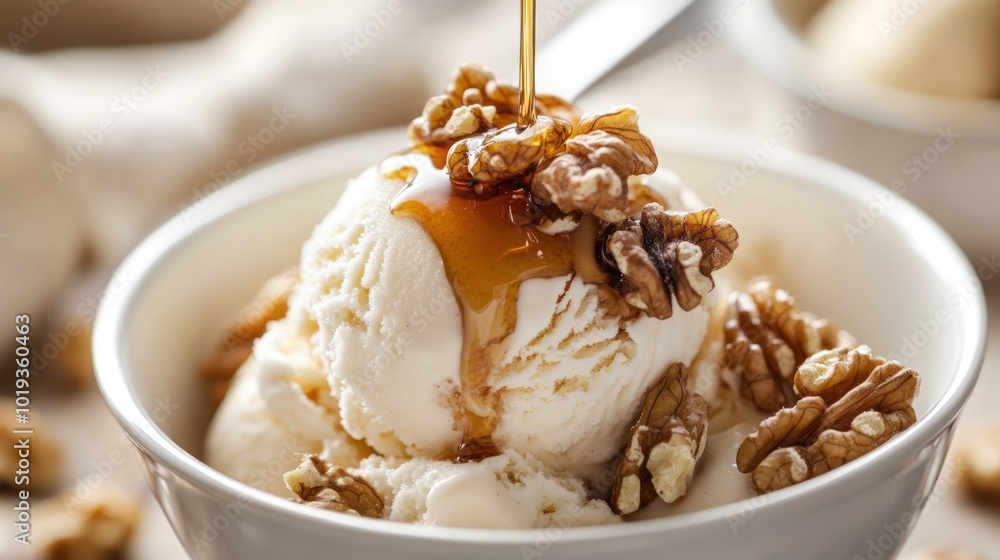 A scoop of vanilla ice cream topped with chopped walnuts and a drizzle of caramel sauce in a white bowl.