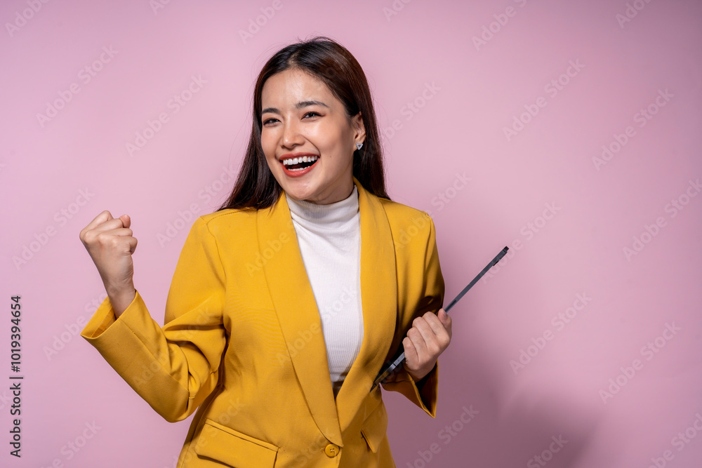 A woman in a yellow jacket is holding a tablet and smiling A woman in a yellow jacket is holding a tablet and smiling