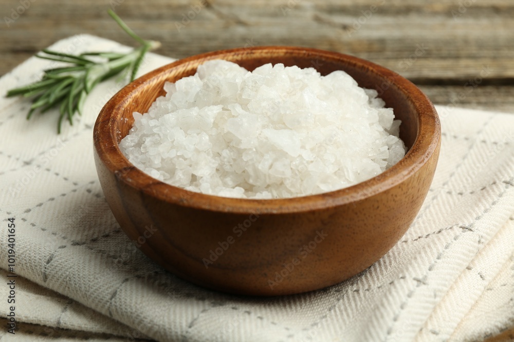 Sea salt in bowl and rosemary on table, closeup Sea salt in bowl and rosemary on table, closeup