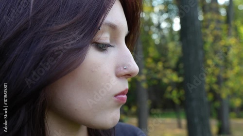 girl licks melted cream ice cream dripping down a waffle cone, a close-up of a face with nose, eyebrow and tongue piercings.