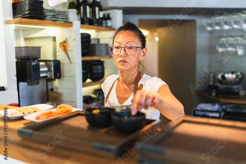 Korean Chef Finalizing Plates for Service Behind Counter photo