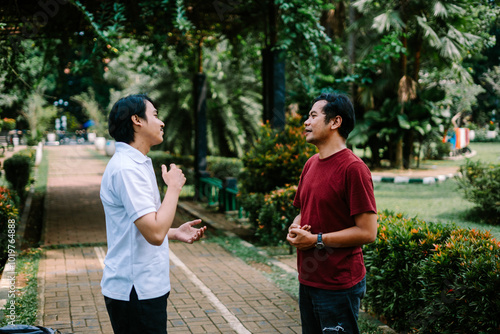 Two Southeast Asian men engaged in a lively conversation at a city square. photo