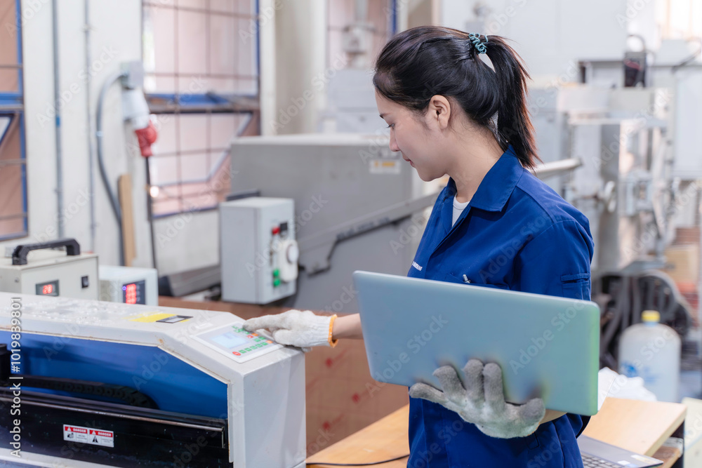 Asian woman industrial engineer wearing uniform using laptop checking and control automated machine in industrial workshop. Asian woman industrial engineer wearing uniform using laptop checking and control automated machine in industrial workshop.