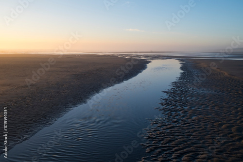 Tide pools on expansive beach at dusk photo