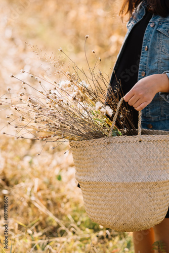 Hand holding basket with wildflowers in nature scene photo