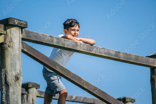 Wallpaper Mural Young boy enjoying a sunny day while leaning on a wooden fence Torontodigital.ca