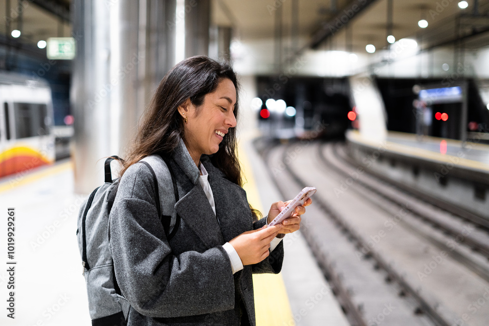 A business woman smiling while using a phone and waiting for the train A business woman smiling while using a phone and waiting for the train