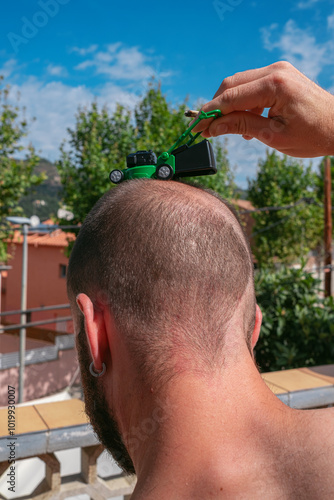 Toy Lawnmower on Man's Bald Spot photo