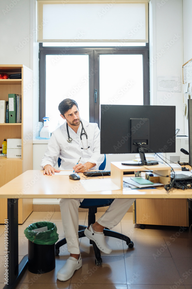 Doctor working at desk with computer in office Doctor working at desk with computer in office