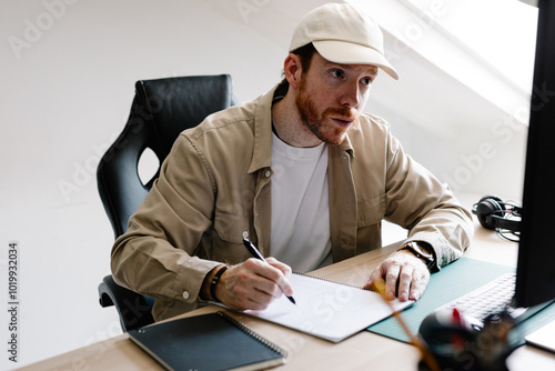 A freelancer makes handwritten notes during a virtual meeting photo