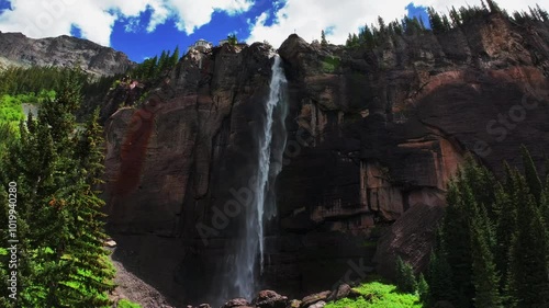 Telluride Bridal Veil Falls aerial drone Waterfall Telluride windy mist spray Black Bear Pass Road Colorado pine tree Ouray Ridgway Box Canyon cliffside 4wd hiking cloudy sun blue sky upwards jib photo