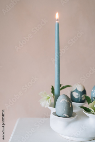 Candle with blue candle and decorated eggs in holder vase. photo