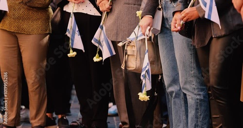 People hold the Israeli flag and flowers during a ceremony commemorating the October 2023 attacks on Israel.