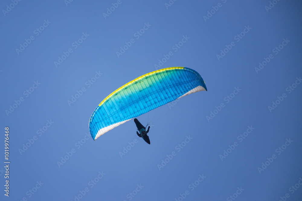 A man with a paraglider in front of a blue sky. A man with a paraglider in front of a blue sky.