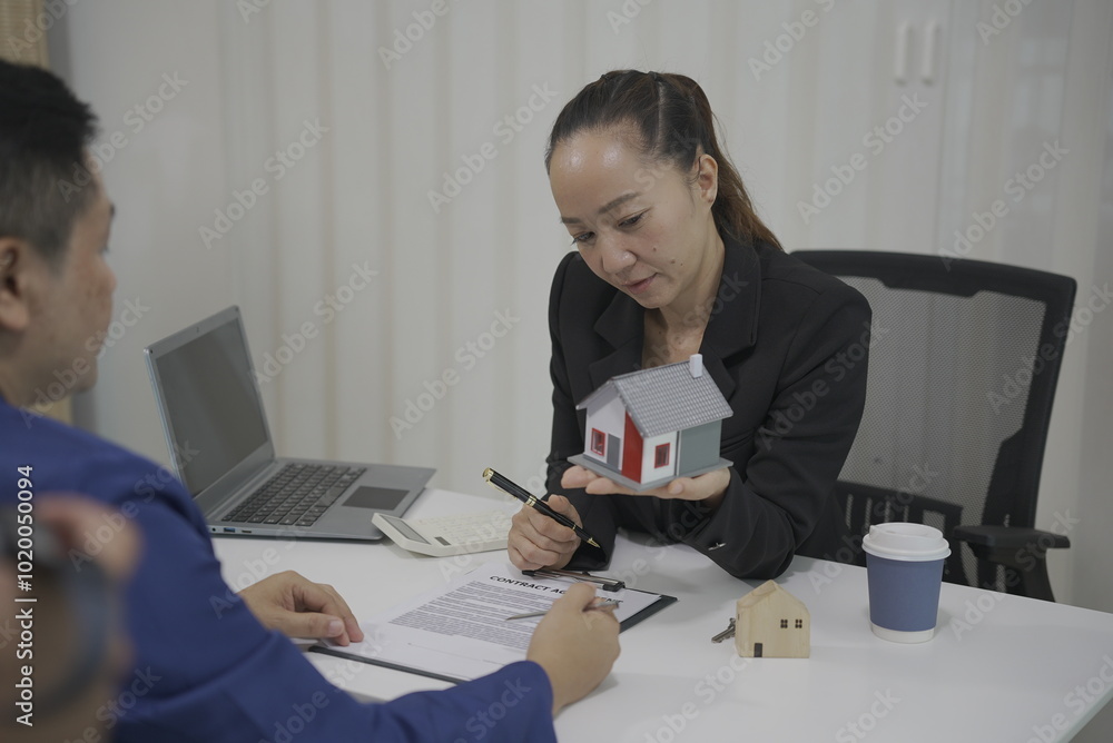Real estate trading concept, home sales agent, sales agent introduces details of housing in the project to interested customers with house samples on the table. Real estate trading concept, home sales agent, sales agent introduces details of housing in the project to interested customers with house samples on the table.