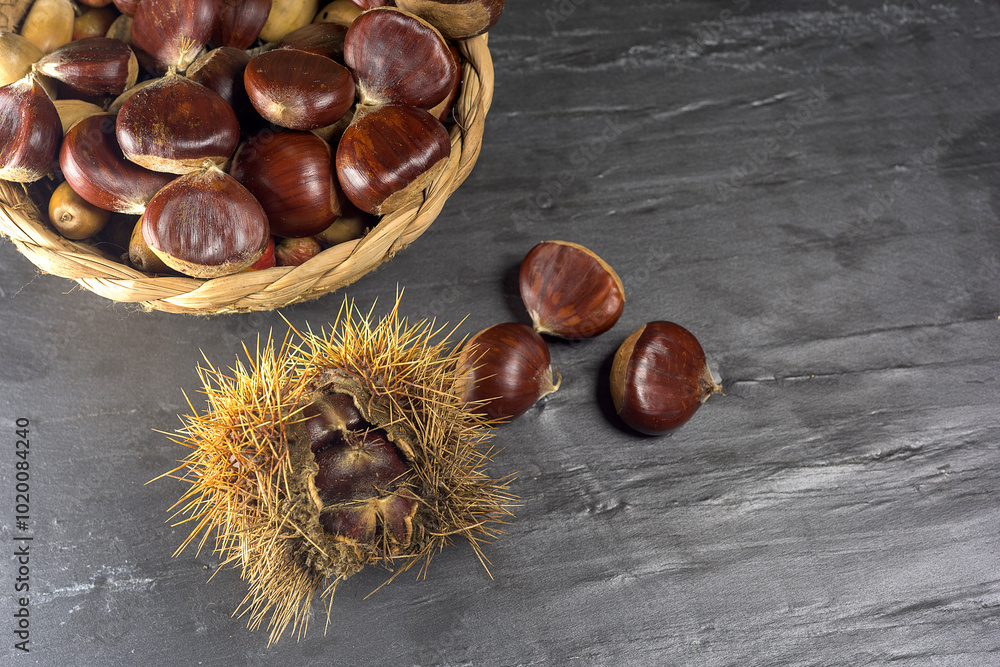 Chestnuts and autumn leaves on black background
