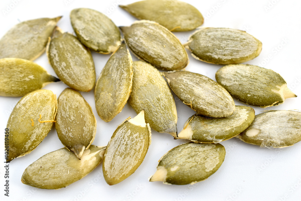Obraz premium A pile of peeled pumpkin seeds lies on white.