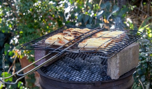 Traditional South African braai broodjies aka toasted sandwiches prepared on a braai fire in the outdoors photo