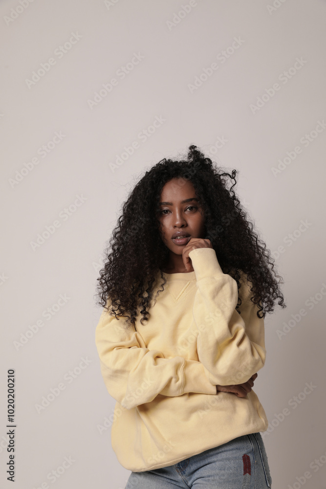 Lovely teenage girl with dark skin afro hair poses against white background dressed in casual clothes. Lovely teenage girl with dark skin afro hair poses against white background dressed in casual clothes.