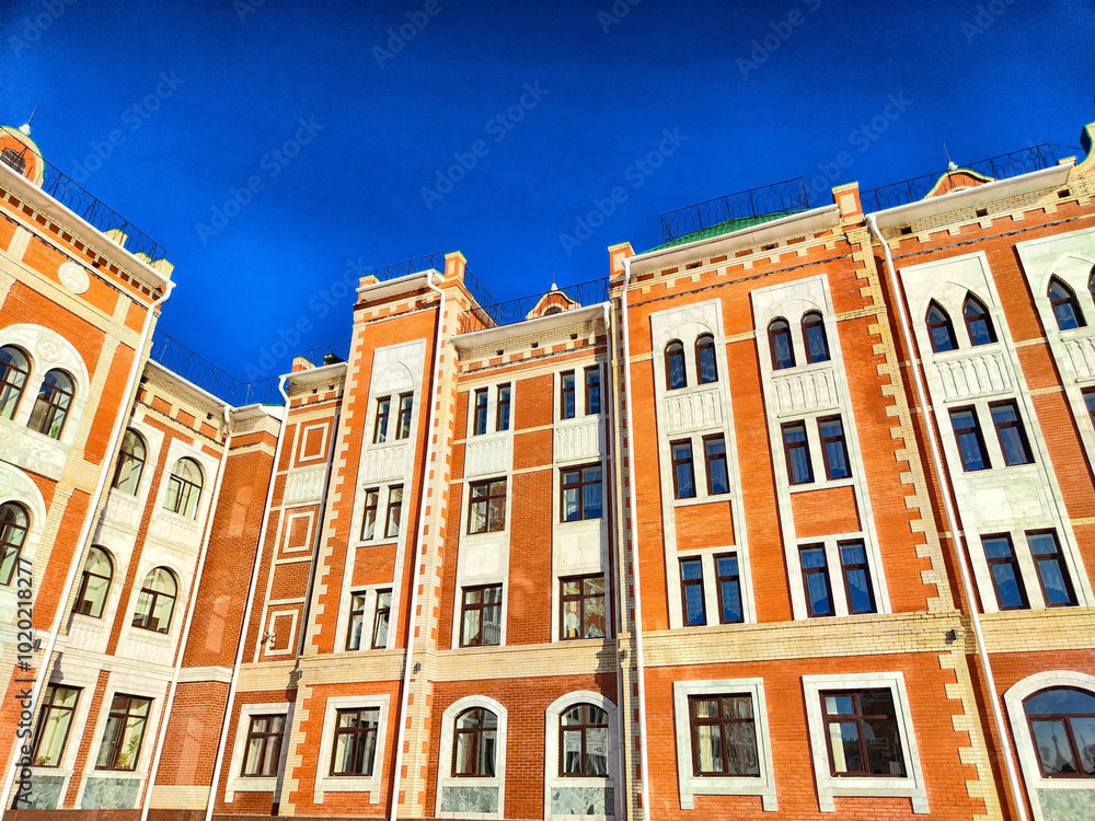 Fototapeta premium Brightly colored historic building exterior under a clear blue sky in an urban setting during daylight hours