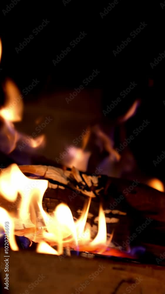 Wooden logs burning in vivid flame in dark. Burning fire in fireplace. Warm fire flames in a country house. Home hearth. Close-up. Vertical video Wooden logs burning in vivid flame in dark. Burning fire in fireplace. Warm fire flames in a country house. Home hearth. Close-up. Vertical video
