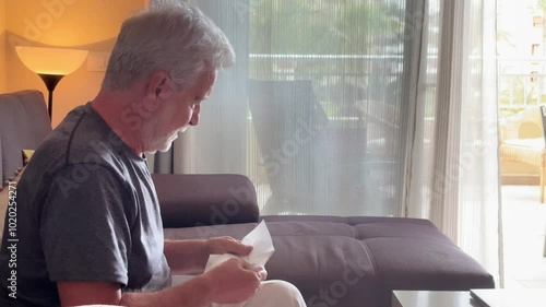 A touching portrayal of an elderly widower crying on his sofa at home, grappling with grief and the isolation that comes with aging. This video captures the deep emotional struggles of senior loneline photo