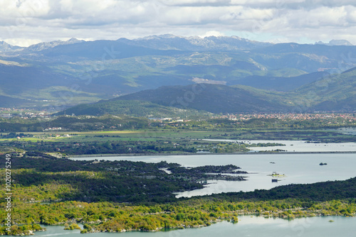 Landscapes of central Montenegro: a mountain range, a lake with many wooded uninhabited islands and the town of Niksic built in a valley. View taken over Slano Lake during a tourist trip to Niksic. photo