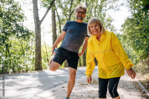 Doing warm up exercises. Senior couple together outdoors at nature