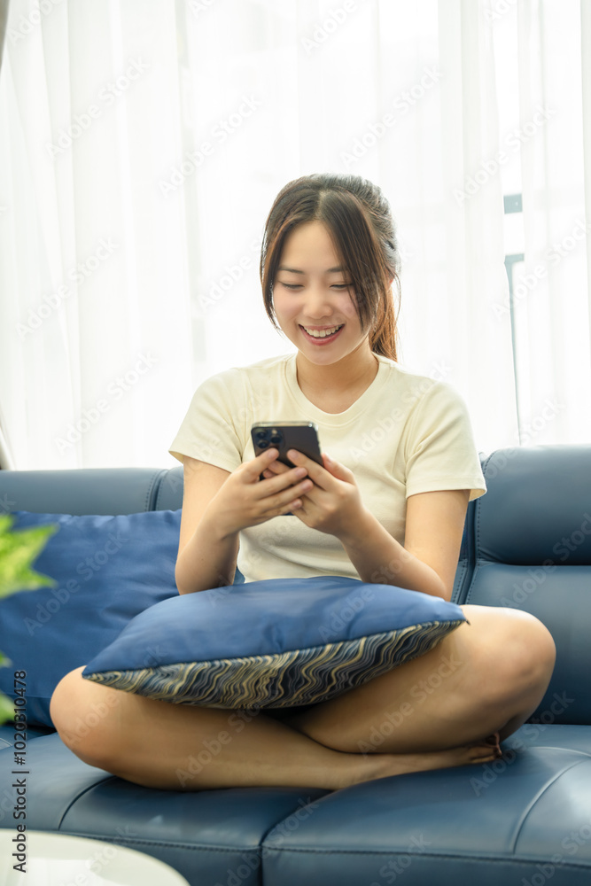 Obraz premium Image of young Asian girl using phone and relaxing at home