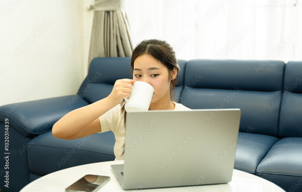 Portrait of young Asian girl using laptop and drink coffee , at home Portrait of young Asian girl using laptop and drink coffee , at home