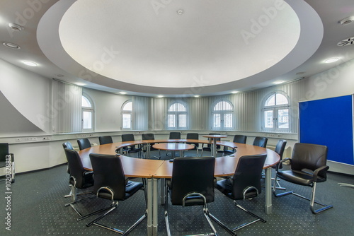 A room for business meetings in a corporate office. A large round table with comfortable .chairs.