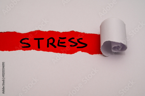 Red surface, with the word Stress in black, under torn and rolled white cardboard. photo