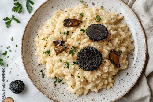 Delicious risotto topped with black truffles and garnished with fresh herbs on a rustic plate. photo