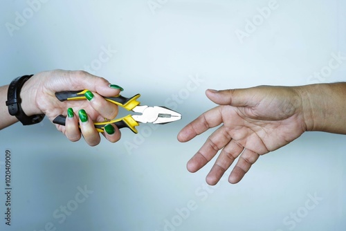 Woman's hand holding a hand tool extended to a business partner, symbolizing teamwork and cooperation in business.