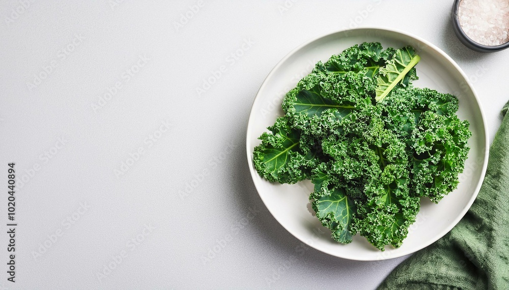 Green kale leaves on white plate, top view.