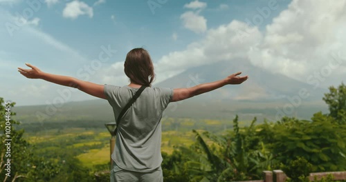 Young woman is embracing the breathtaking beauty of a tropical landscape, with the majestic mayon volcano standing tall in the distance