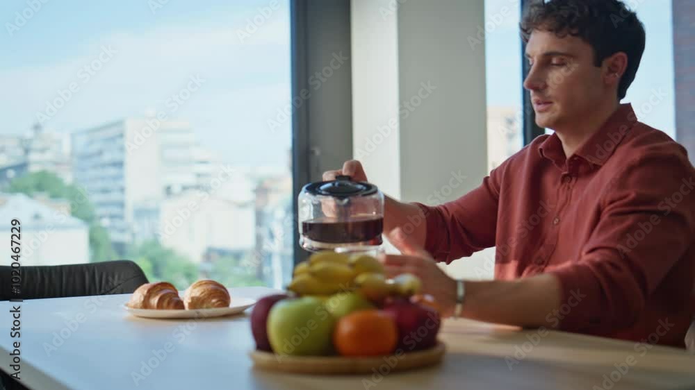 Serious guy pouring coffee at home morning closeup. Calm man filling glass cup