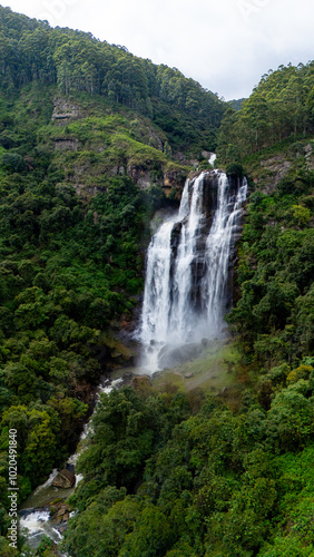 Lush Sri Lanka's majestic waterfall. A stunning waterfall flows through vibrant greenery in Sri Lanka, creating a tranquil atmosphere amidst nature's beauty.